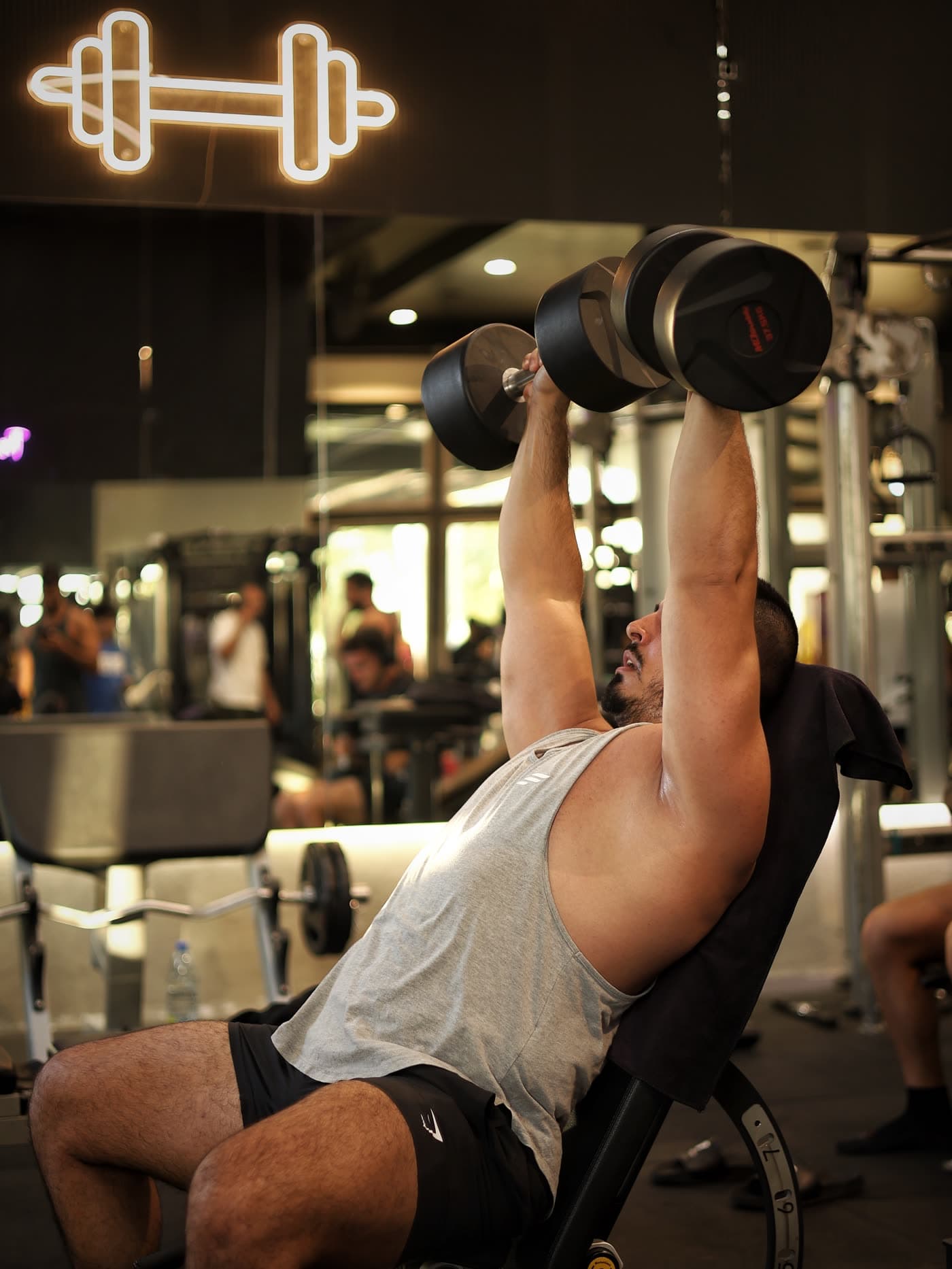 Incline dumbbell press under the neon dumbbell sign